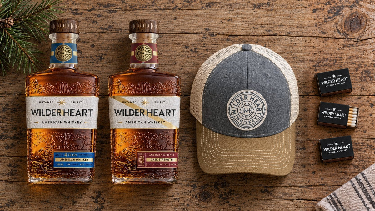 The Long Weekend laid out on a weathered pine table: Wilder Heart Whiskey, Cask Strength, the Richardson 112 trucker and three Wilder Heart matchboxes