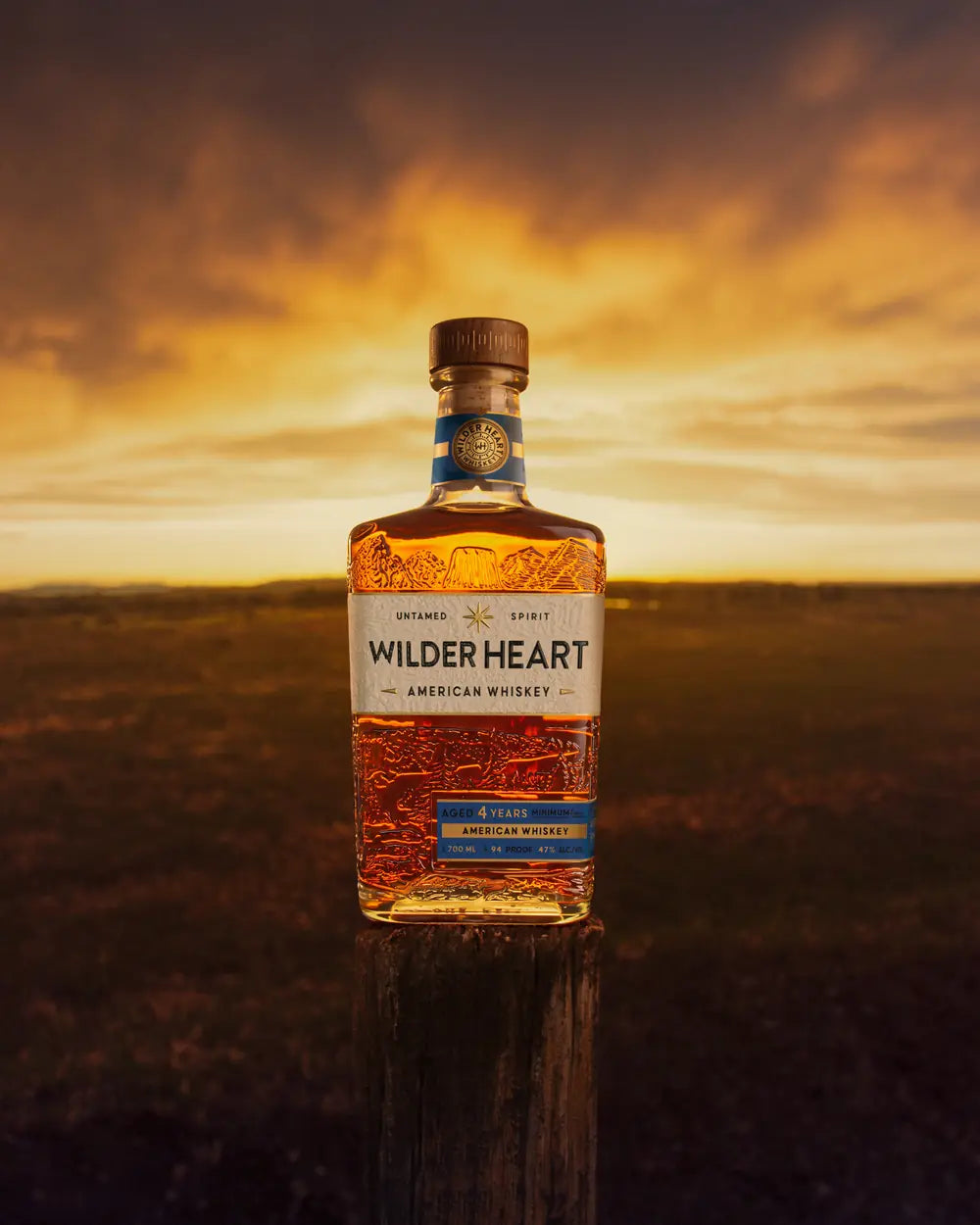 A bottle of Wilder Heart against a sunset sky